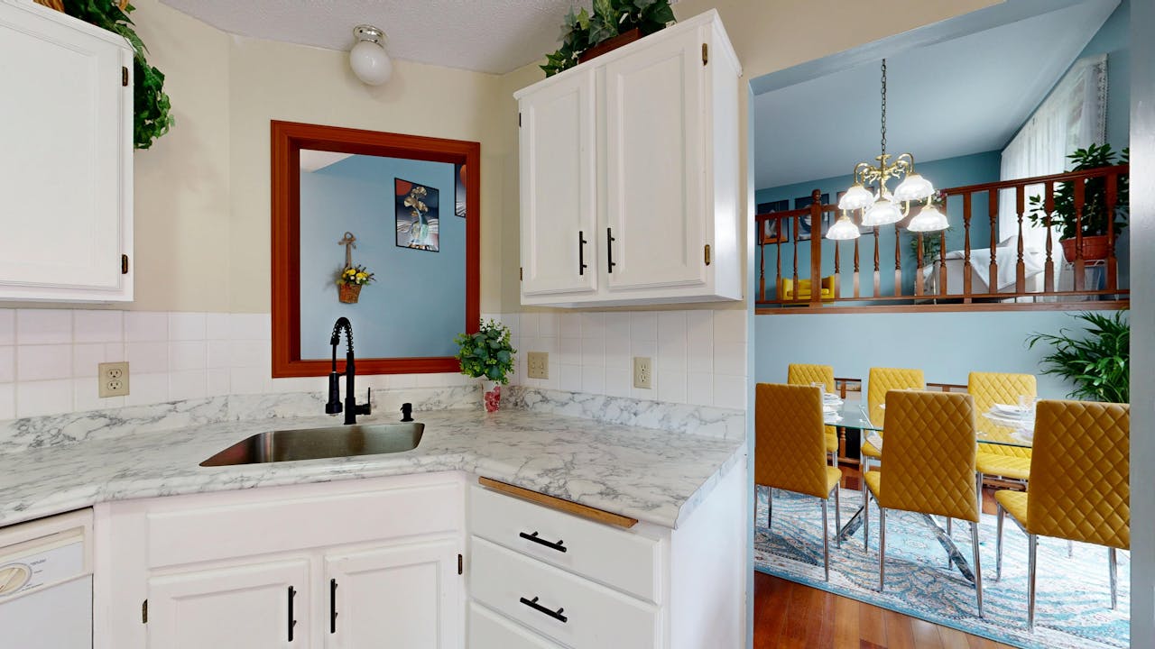 Bright modern kitchen with marble countertops overlooking a stylish dining area.